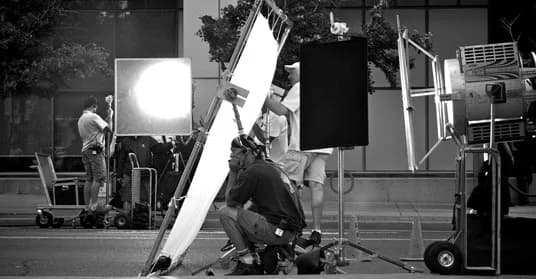 A film crew setting up lights on a city street